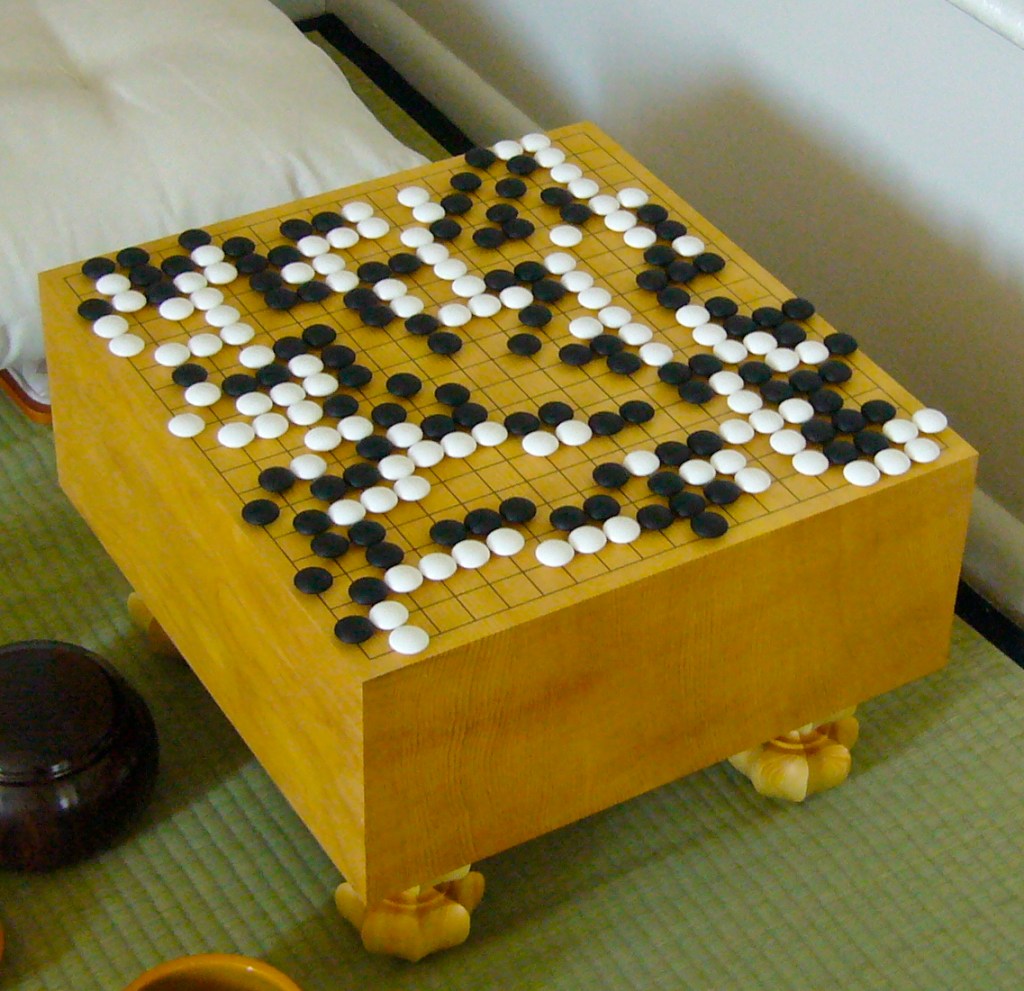 A wooden Go board mid game. Picture: public domain. https://en.wikipedia.org/wiki/Go_(game)#/media/File:FloorGoban.JPG